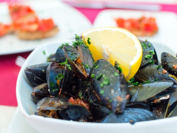Mussels in a bowl with lemon wedge and parsley on top