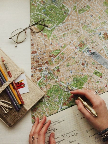 how to plan your next vacation, picture of map, notebook, and a woman's hands holding a pen