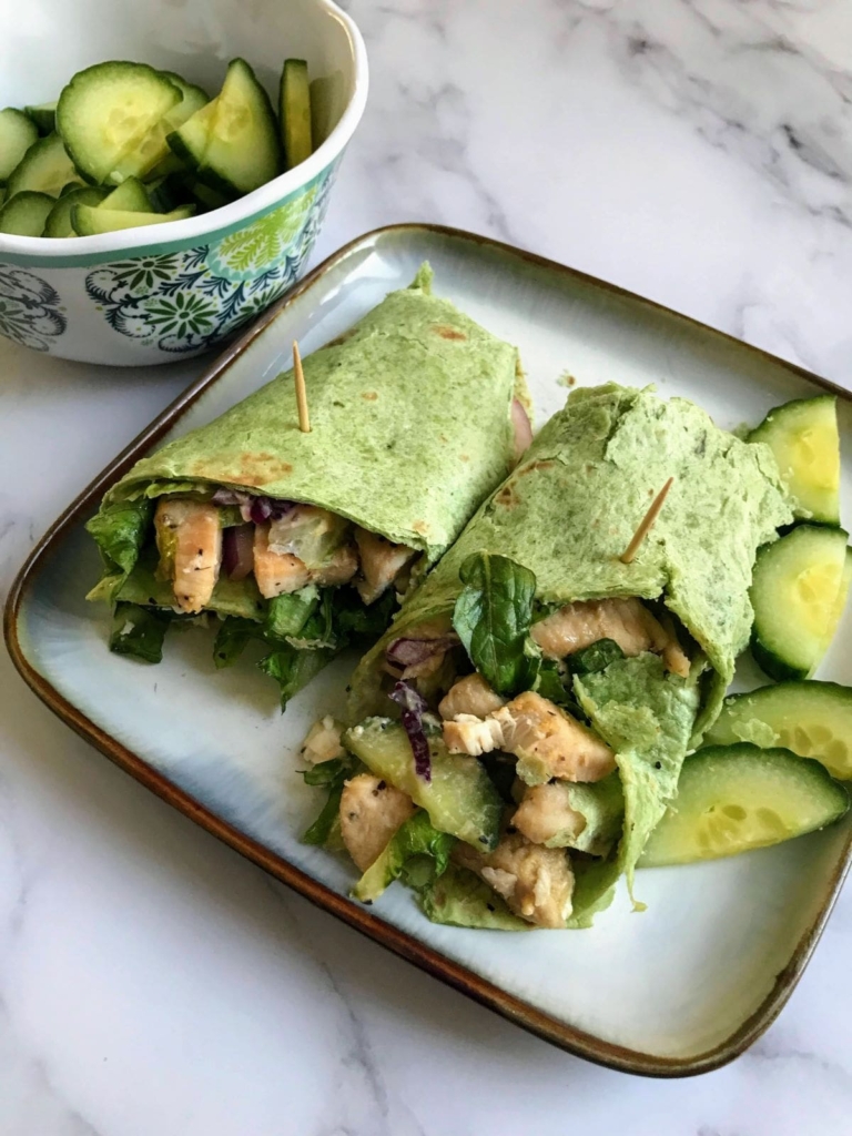 Mediterranean wrap with chicken and red bell peppers on a plate with cucumbers