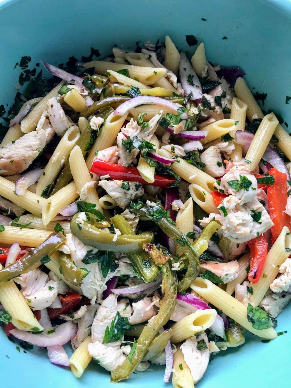 ingredients for chicken bell pepper pasta salad mixed in a blue bowl.
